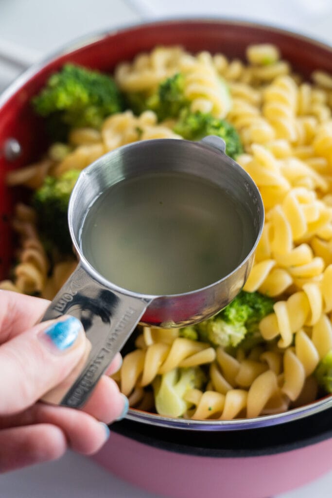 water in measuring cup behind held over pasta.