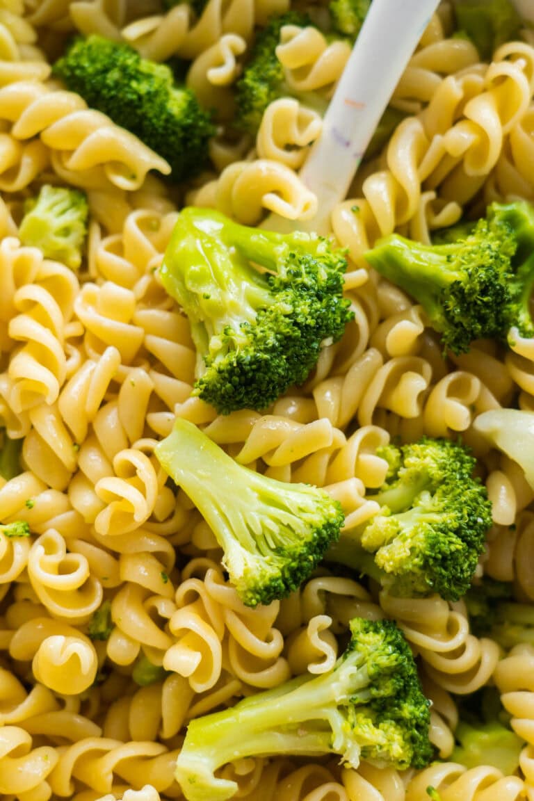 A delicious plate of butter garlic pasta mixed with fresh green broccoli florets.