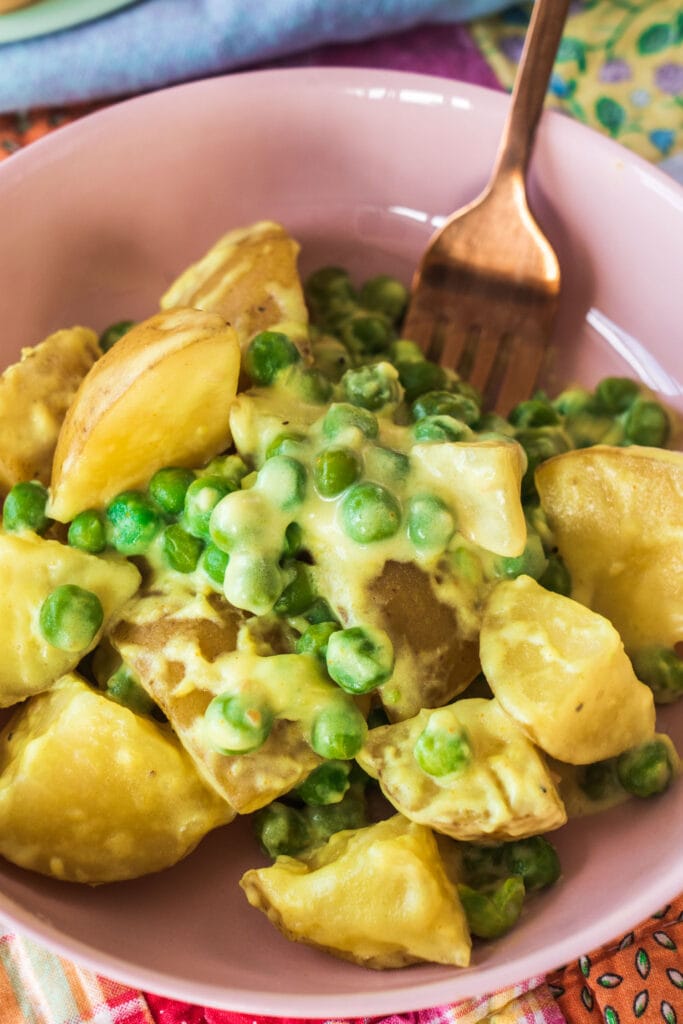 potatoes and peas in pink bowl with a fork. 