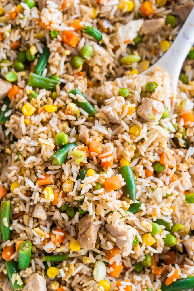 pork fried rice in skillet with spoon serving it