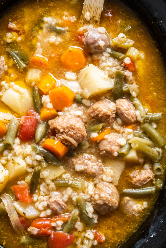 slow cooker filled with sausage, barley and vegetables.