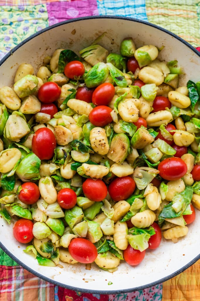 skillet filled with gnocchi, brussels sprouts and tomatoes.
