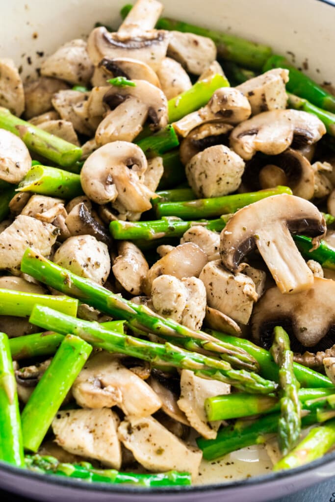 chicken, mushrooms and bright green asparagus being cooked.