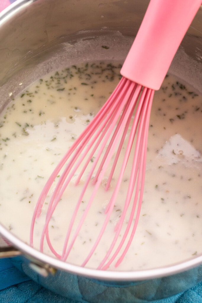 pink whisk mixing cream sauce.