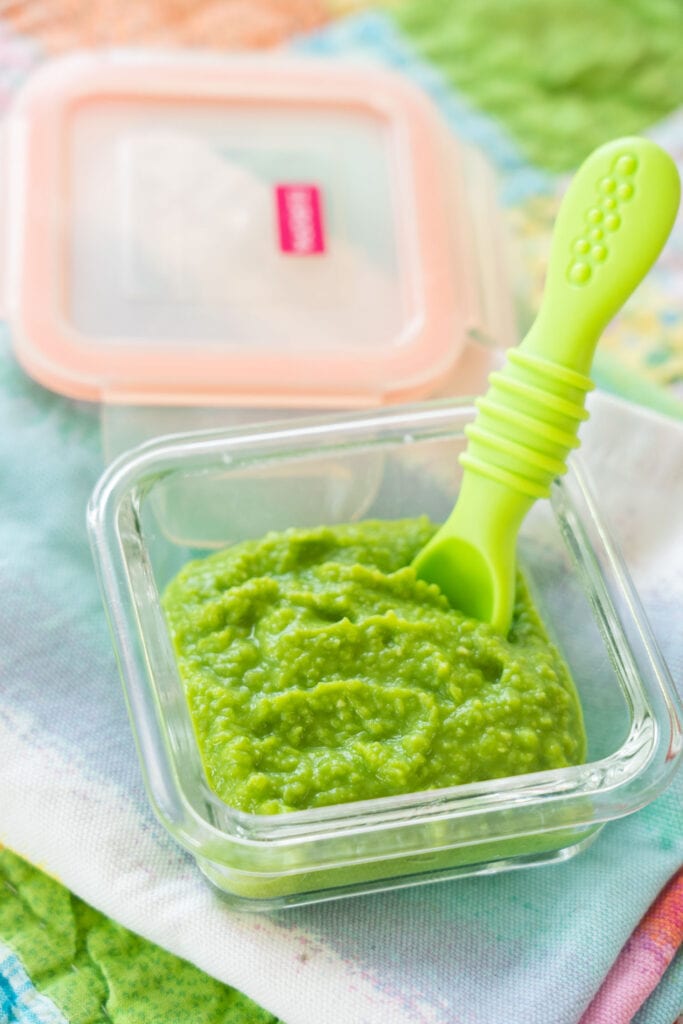 baby food in glass jar with green spoon in it.