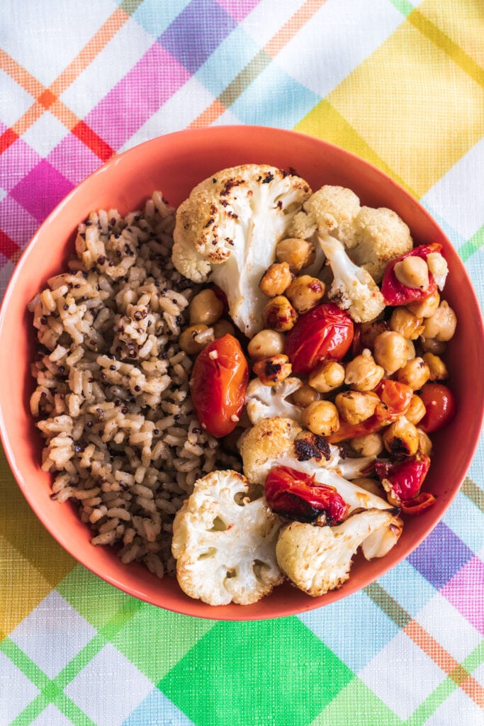 bowl of roasted cauliflower, chickpeas and tomatoes served next to rice.