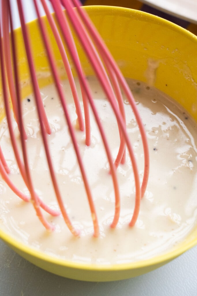cream sauce being whisked in yellow bowl. 
