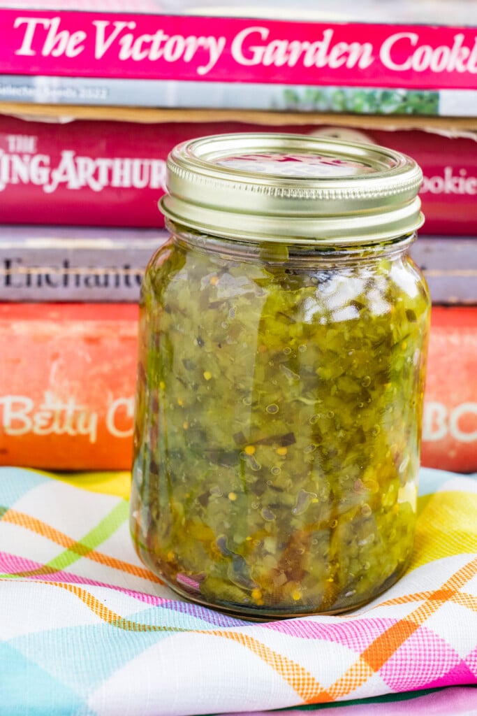 mason jar filled with relish in front of books.