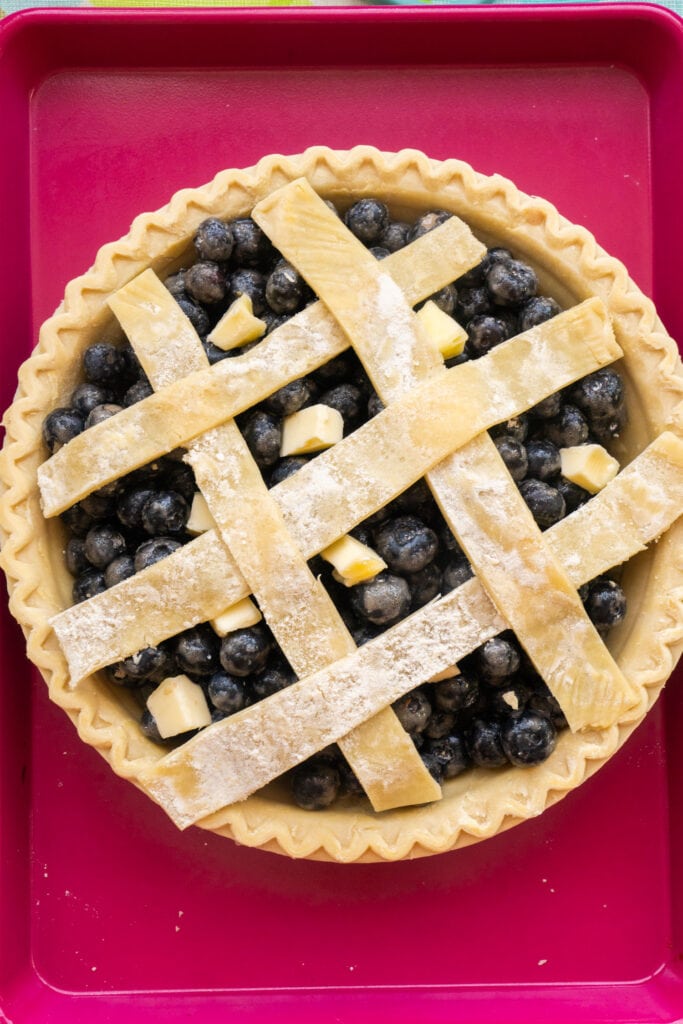 pieces of dough added to top of blueberry pie to make design.