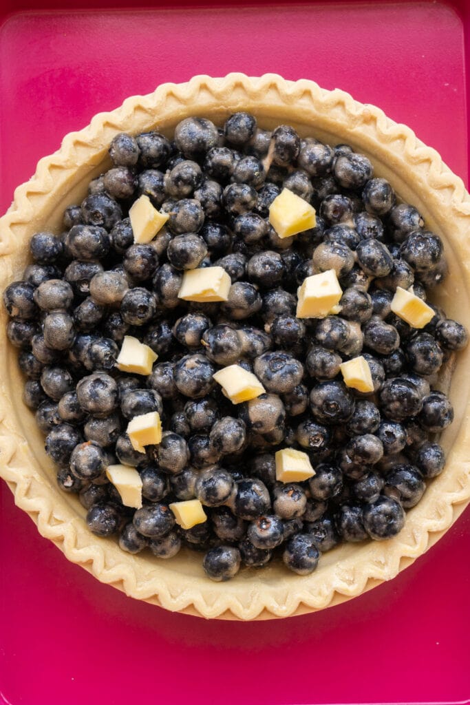 small pieces of butter on top of blueberry pie.