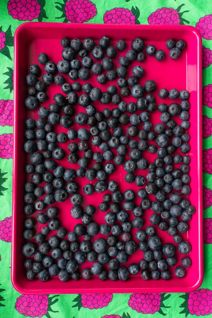 blueberries on pink baking sheet.