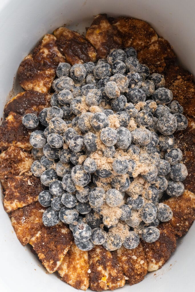 blueberries in middle of slow cooker surrounded by biscuit pieces.