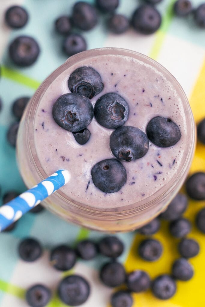 closeup of blueberry smoothie with blue straw coming out of it.