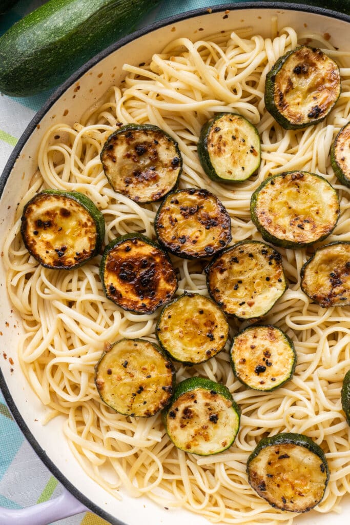 zucchini pasta in skillet with linguini noodles and browned zucchini.