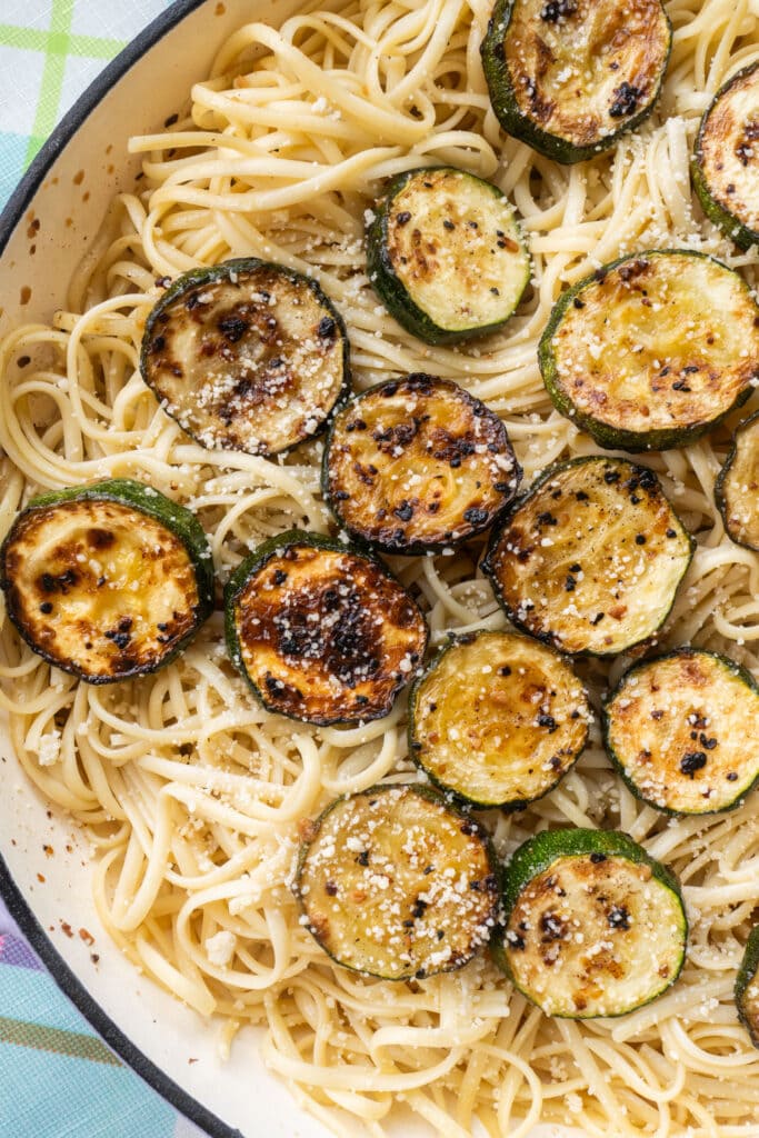 browned zucchini over pasta in skillet.