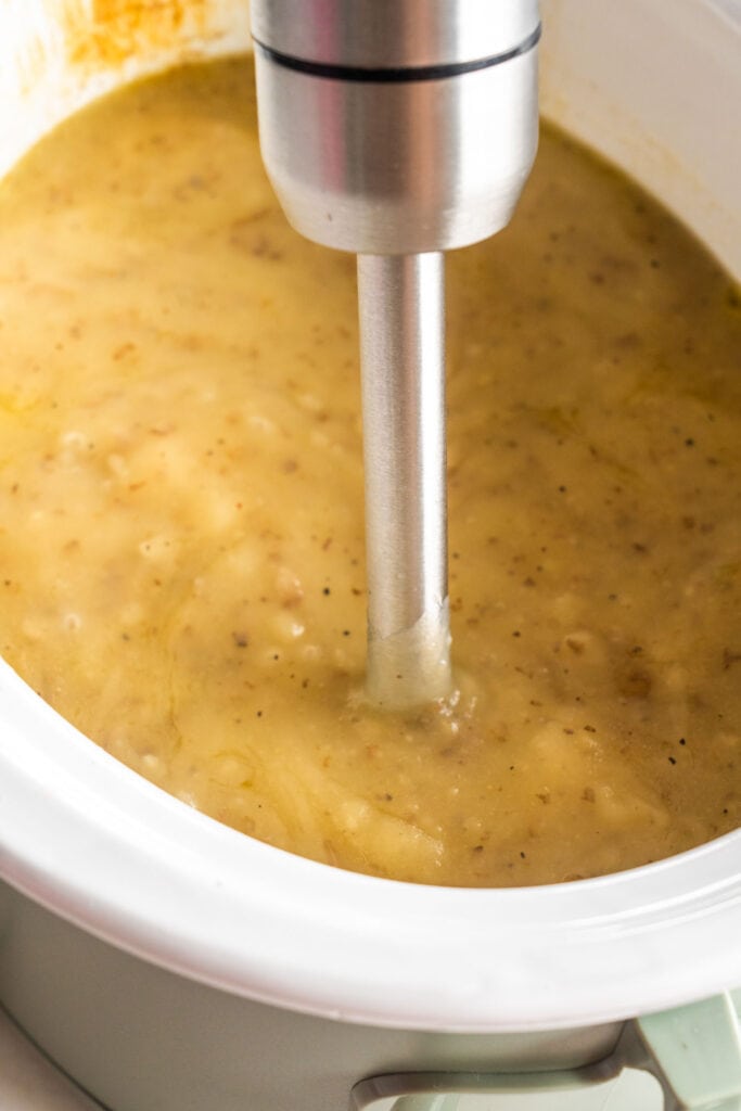 immersion blender blending soup in slow cooker until creamy.