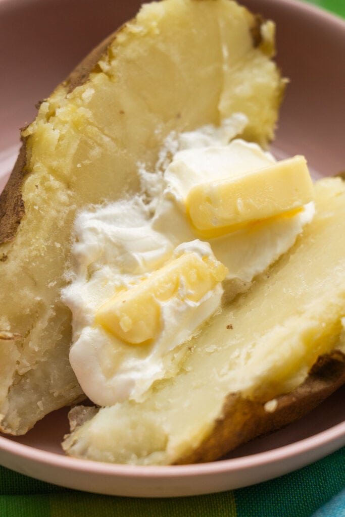 fluffy baked potato split open with butter and sour cream.