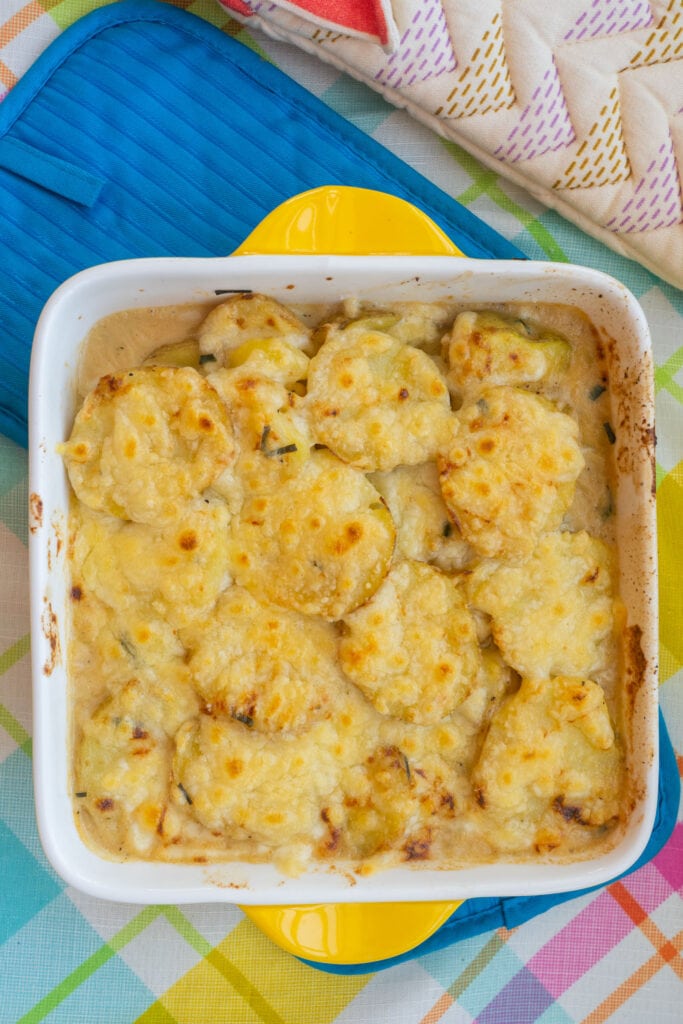 cheesy baked browned potatoes in yellow baking dish.