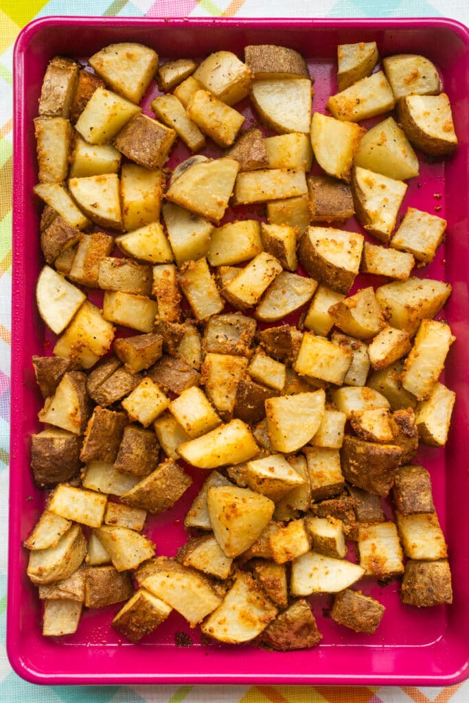 roasted potatoes on pink baking sheet.