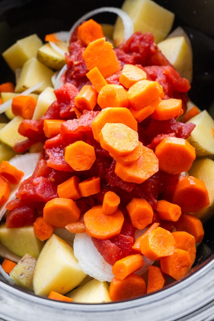 sliced carrots added on top of vegetables in slow cooker.