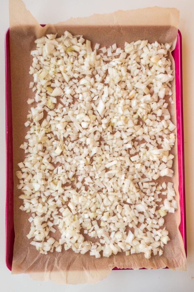 chopped up onion on parchment paper on baking sheet.