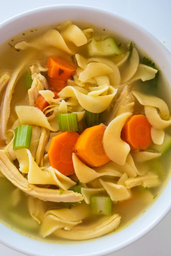 bowl filled with chicken noodle soup with vegetables and broth.