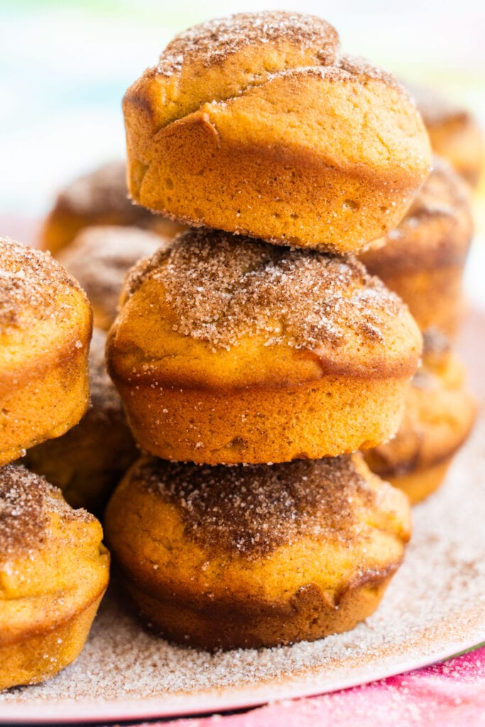 stack of pumpkin muffins with cinnamon sugar sprinkled on top of each one.