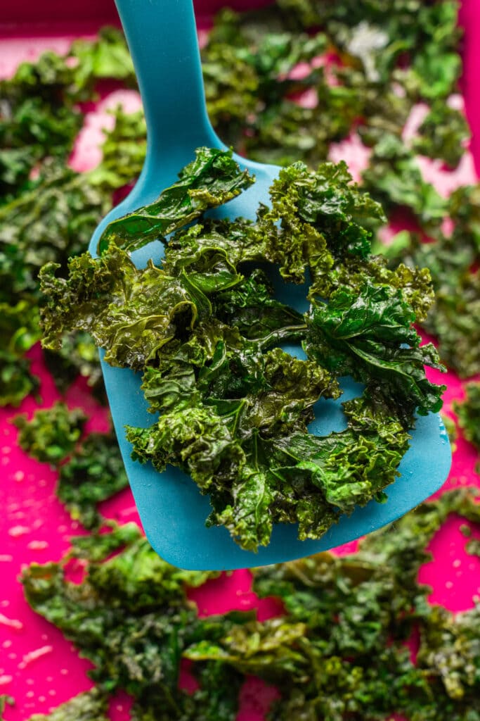 spatula lifting out kale chips from baking sheet.