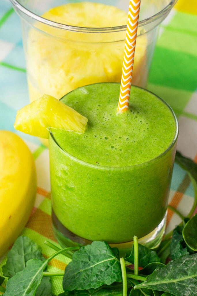 kale smoothie in glass cup with straw.