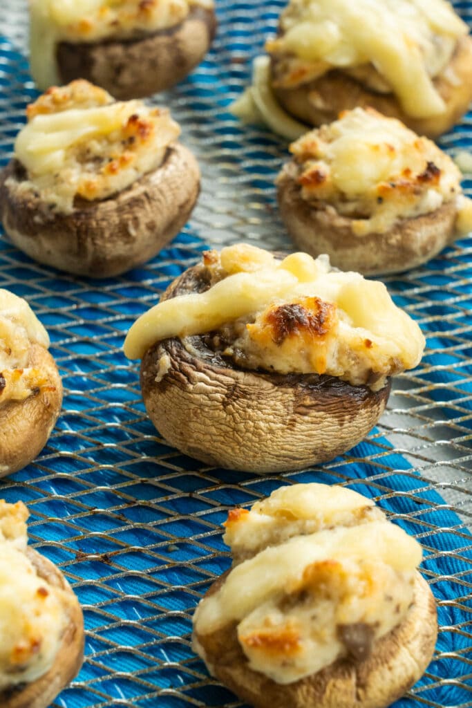 stuffed mushrooms on air fryer basket with browned cheese on top.