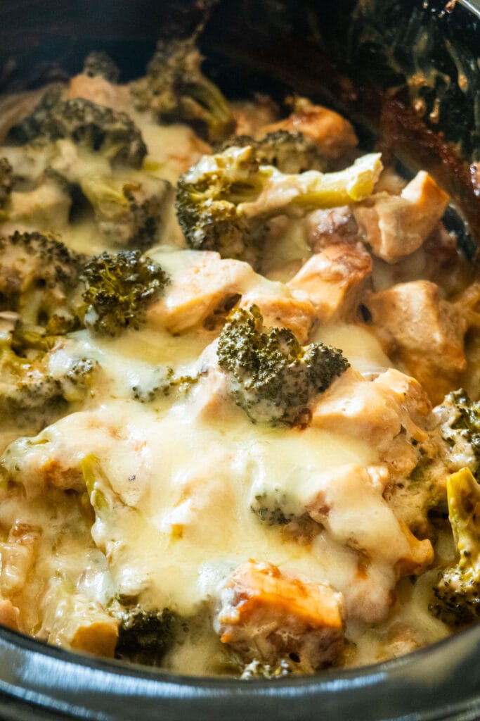 melted cheese on top of chicken and broccoli in slow cooker.