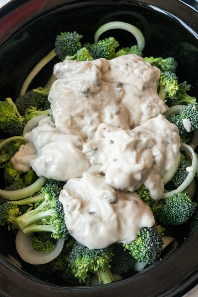 cream of mushroom soup added into slow cooker on top of broccoli.