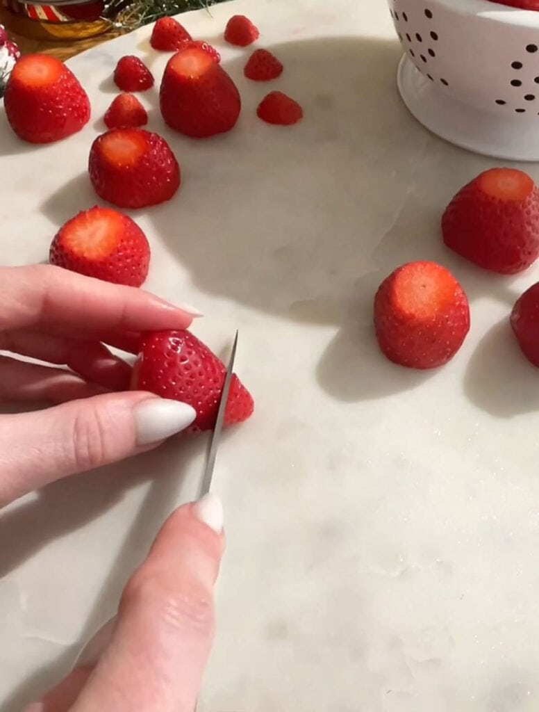hand cutting strawberry to make hat and body for santa.