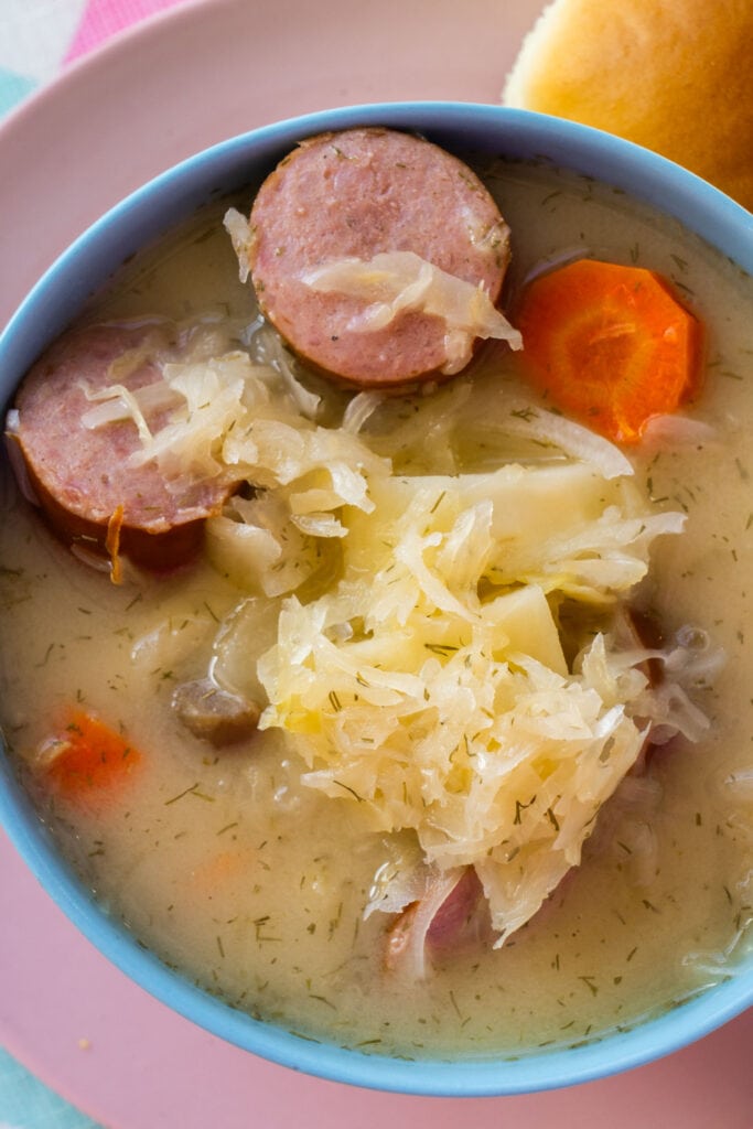 closeup of sauerkraut soup with sausage and vegetables.