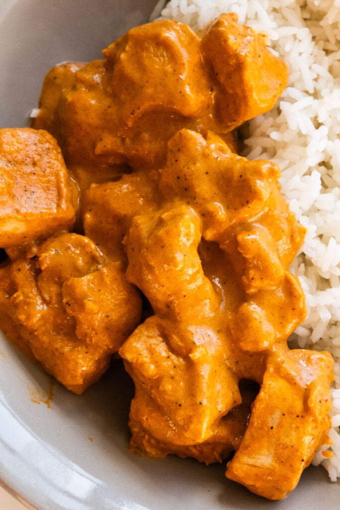 butter chicken served with rice on plate.