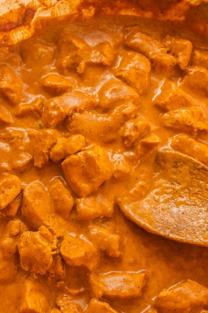 creamy butter chicken in skillet with spoon.