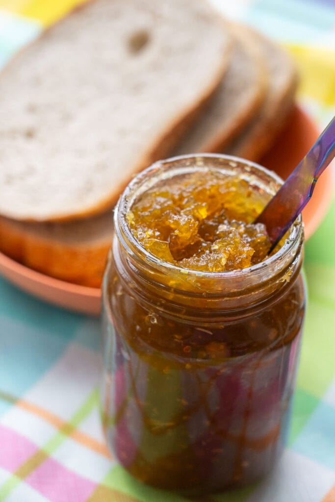 jam in jar with bread in the background.