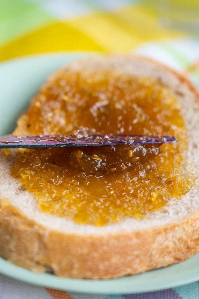 knife spreading jam on piece of bread.
