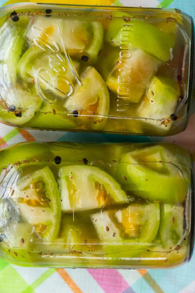 mason jars laying on side filled with pickled green tomatoes.