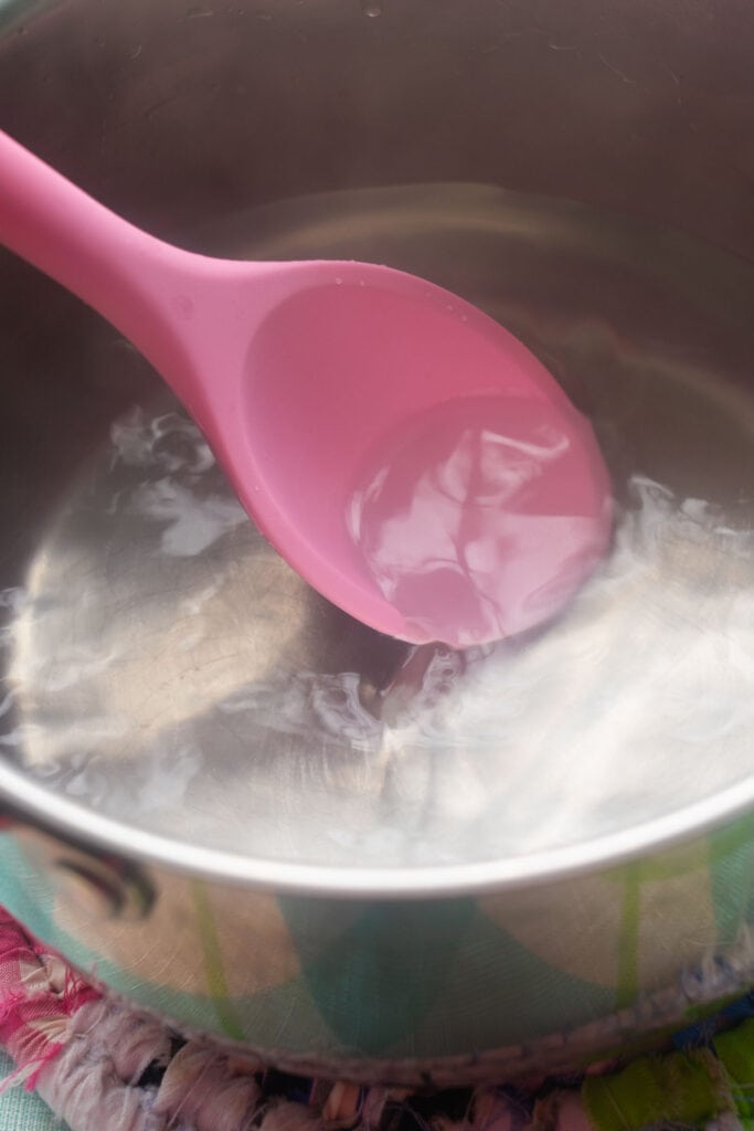pink spoon stirring salt water.