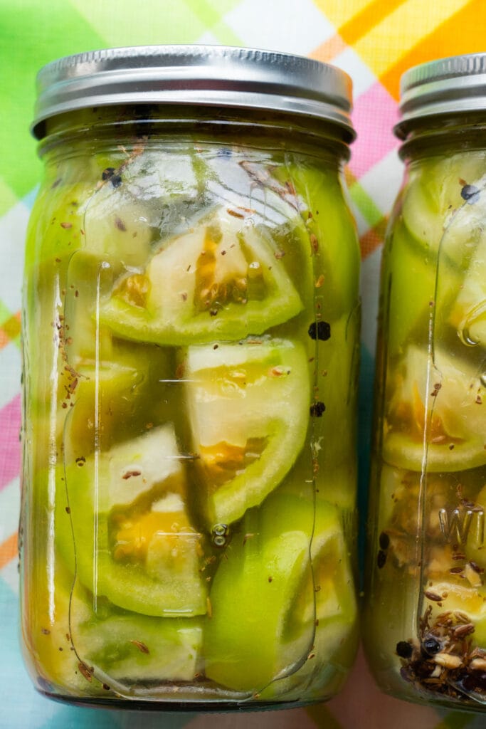 jars of pickled green tomatoes with spices.