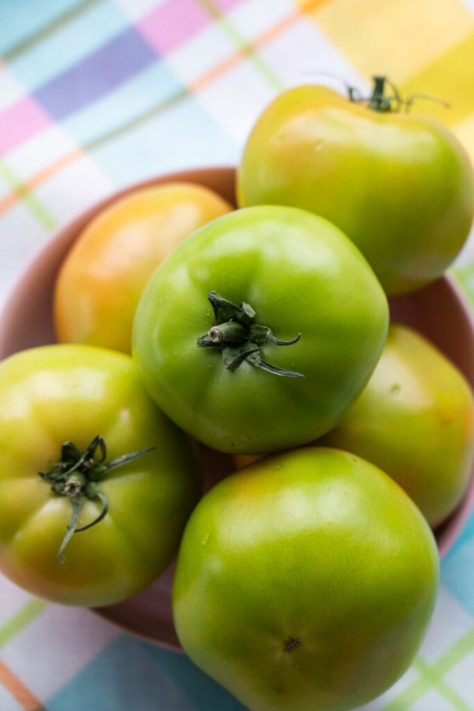 green tomatoes in bowl on table.