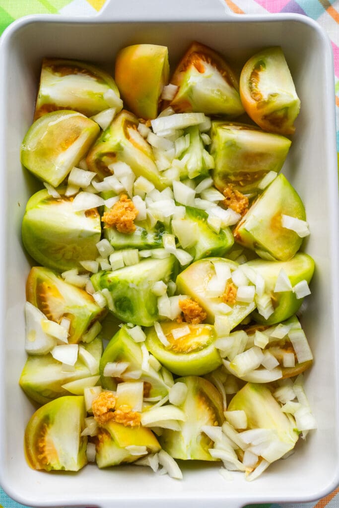 green tomatoes, onions and garlic in baking dish.