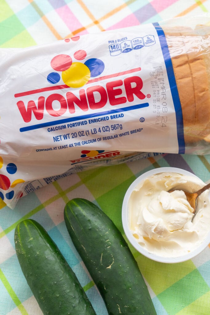wonder white bread, cucumber and cream cheese on table.