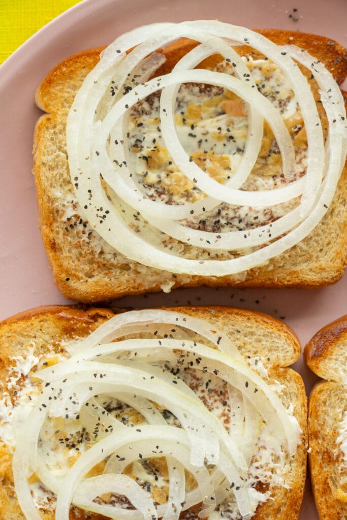 onions and cream cheese on bread with sprinkle of salt and pepper.
