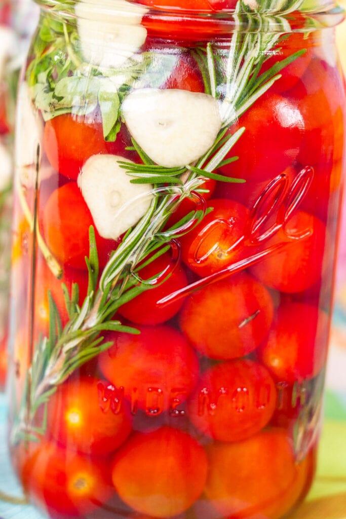 closeup of pickled cherry tomatoes in jar.