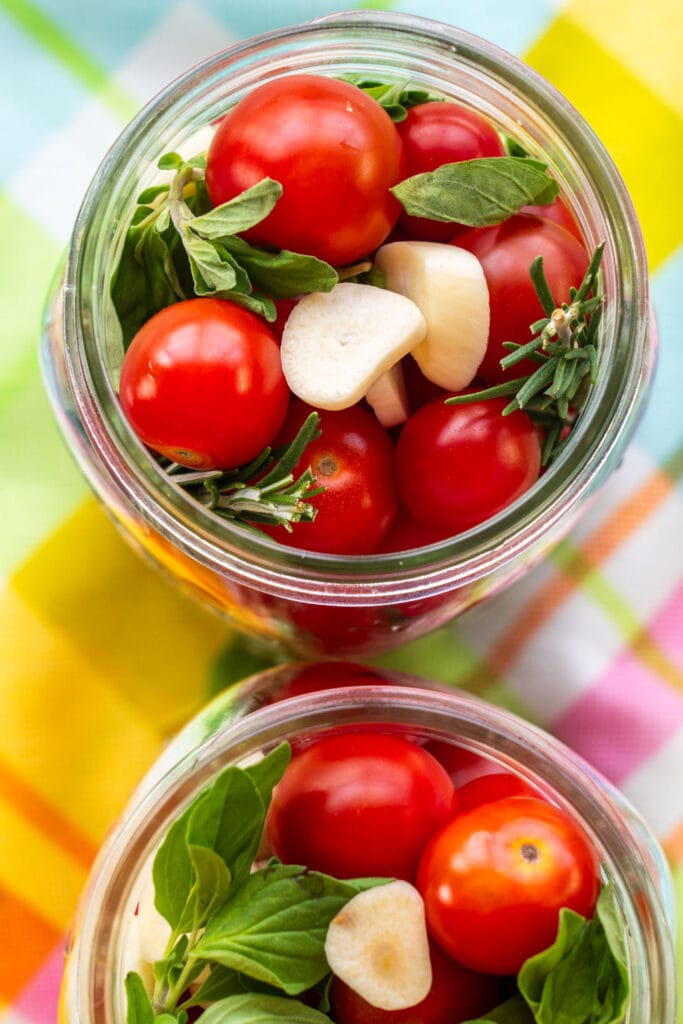 cherry tomatoes with minced garlic and fresh herbs in mason jar.