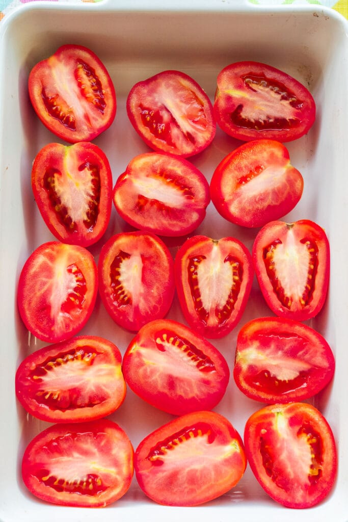 roma tomatoes cut in half in baking dish.