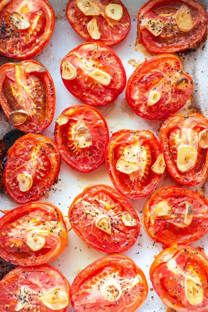 roasted roma tomatoes with garlic in baking dish.