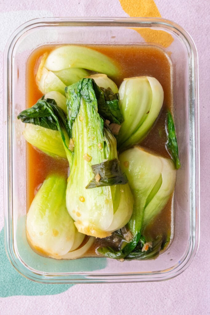 bok choy and sauce being stored in glass container.